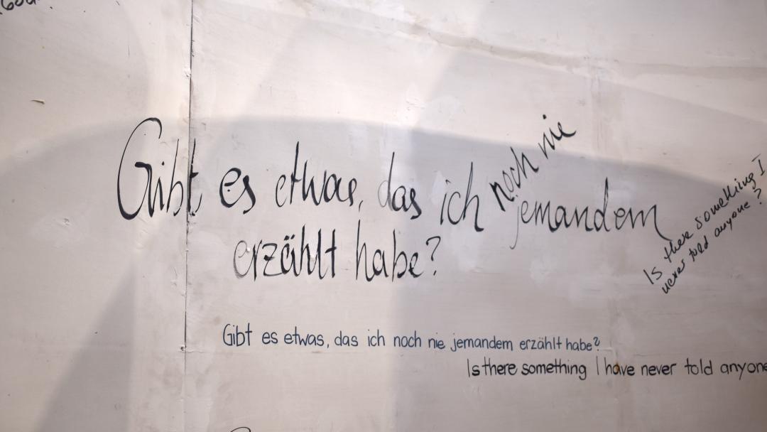 in mehreren Handschriften steht auf weißer Wand: "Gibt es etwas, das ich noch nie jemandem erzählt habe?"